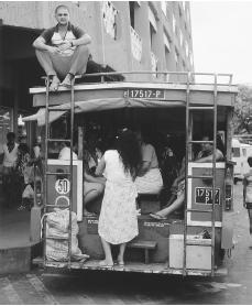 A passenger rides on top of the Papeete bus in Tahiti. Papeete is the only urban center in French Polynesia.