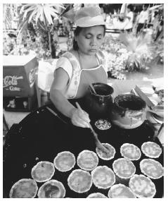 A Mexican woman prepares tortillas with salsa and beans. Corn, chili peppers, and beans are the main items in most Mexican foods.