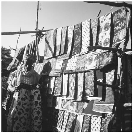 A man sells patterned cloth at a market. Nigerians are expert dyers, weavers, and tailors.