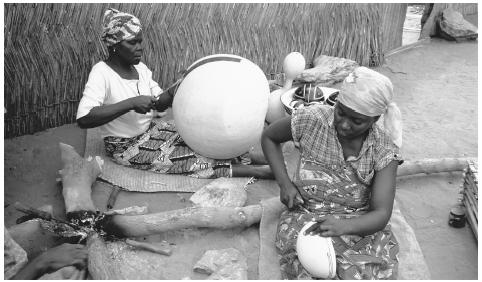 Women engrave designs into yellow calabash gourds. Nigerian art traditionally served a social or religious purpose.
