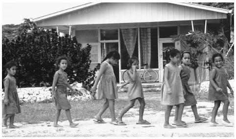 Girls in school uniforms walk along the street. Schooling is compulsory, secular, and free for all children ages 5 to 14.